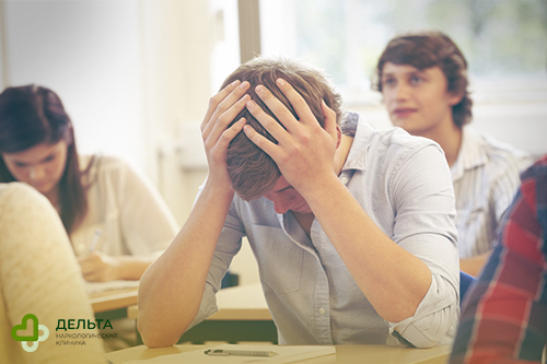 Подросток на уроке держится за голову